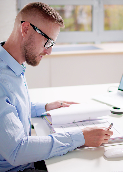 Office worker managing cases on paper with computer open